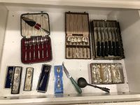 Photo showing the full collection including boxed dessert forks, teaspoons, steak knives, collector spoons, apple-shaped holders, and ring boxes.