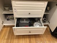 Drawer containing various bakery pans including muffin tins, cake pans, and round covered cake pan.