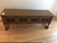 Full view of the wooden TV stand with four drawers and carved fronts.