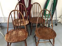 Four vintage wooden chairs, one with broken seat, two heavily worn, spindle back style.