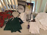 Overview photo showing the pillows, folded cloth napkins, towels, and tablecloths spread on floor near stair railing.