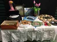 Full view of items on table showing flamingo figurine, VHS camcorder, tropical books, shell wreath, decorative frames, and assorted holiday items.