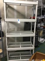 Photo of full white plastic shelving unit with four slatted shelves