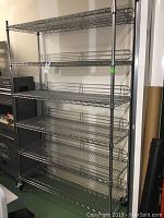 Full view of large chrome wire shelving unit with 5 shelves and wheels