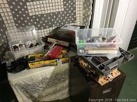 Overview of lot items showing plastic organizers with art supplies and gray plastic tool accessories on top of a wooden file cabinet.