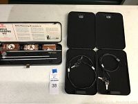 Top-down view of rifle cleaning kit with cleaning rods, solvent, oil, and patches next to two black hand gun vaults with cables and keys inside.