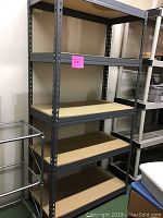 Full view of heavy duty metal storage shelving unit with four particle board shelves, grey metal frame.