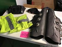 Table displaying all items including shin covers, storage bag, skull cap, and two reflective vests