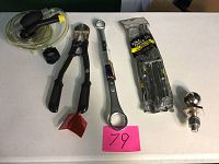 All items laid out on a table, showing lug wrench, bolt cutter, hitch ball wrench, siphon kit, and trailer ball.