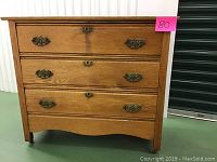 Front view of oak dresser showing three drawers and metal handles with pink lot number sticker.
