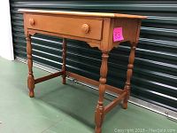 Front and side angle view showing one drawer desk made of maple wood with round knobs and turned legs