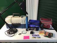 Photo of entire assembly showing the lamp with magnifying glass, treasure boxes, coolers, flashlight, fly tying tool, and some accessory packets