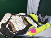 Photo showing all three items: Joe Rocket jacket with leopard print accents, fluorescent yellow reflector vest, and black trip bag with hooks on back.