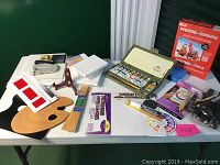 Full view of artist supplies arranged on table including palettes, brushes, canvases, paint tubes, staple gun, and photo to canvas kit.