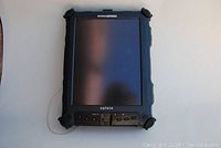 Front view of Xplore iX104 rugged tablet with screen off showing navigation buttons and rugged rubberized edges.