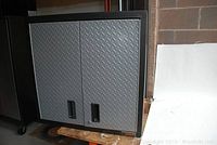 Front view of Gladiator garage wall cabinet showing double diamond plate textured doors and recessed handles.