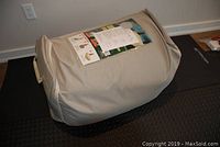Air mattress rolled in beige fabric cover with visible label and instructions attached