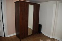 Front view of dark wood wardrobe with three doors, center door having a full-length mirror.