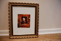 Framed artwork showing full frame and matting, highlighting the decorative golden frame and placement in room context.