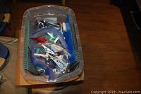Clear plastic bin with gray baseplates lining the sides and multiple resealable bags of assorted LEGO pieces inside