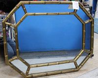 Front view of the octagonal mirror showing the faux bamboo style golden frame against a blue background