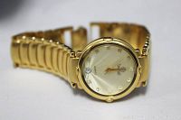 Front and angled side view showing gold electroplated linked band and dial with diamond or crystal hour markers, gold hands, and date window at 3 o'clock.