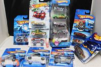 Photo showing 12 Hot Wheels vehicles and one motorcycle in original packaging featuring multiple models including a 5 pc gift pack and various collector edition cars.