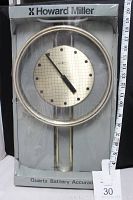 Clock in original packaging, showing front view with tape and measuring tape to confirm size.