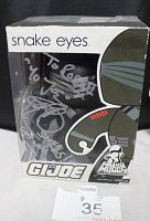 Front angled photo of boxed autographed G.I. Joe Snake Eyes Mighty Muggs figure with silver marker signature on plastic window.