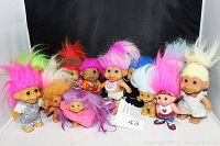 Photo showing 11 vintage troll dolls with colorful hair and various clothing including silver, heart patterns, and floral designs.