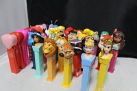Front angled shot showing multiple PEZ dispensers with Disney princesses, Lion King characters, and pink heart-shaped tops.