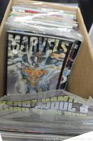 Box of vintage comic books with Marvels comic visible on top