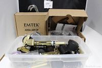 Plastic bin with assorted castors and metal hardware components in front of two EMTEK door handle boxes