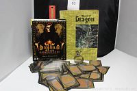 Photo showing a stack of sleeved Magic: The Gathering cards, small pewter dragon, Best of Dragon magazine Vol. V, and Diablo Expansion Set book.