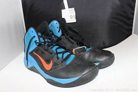 Pair of vintage Nike hi-top basketball shoes, black and blue with orange swoosh, size 9.5 from 2013, shown from angled front-left.