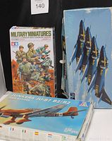 Photo shows three vintage military model kits including a box of Tamiya Military Miniatures German Infantry, Italeri Junkers JU-87 B2/R2 Dive Bomber, and a box with Blue Angels Sky Hawk aircraft.