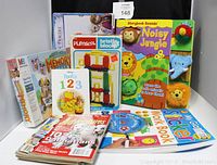 Photo showing all items in the lot arranged upright for display, includes books, games, blocks, stickers, and magazines.