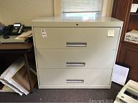 Photo of front side of white metal 3-drawer lateral file cabinet with tape residue and scuffs