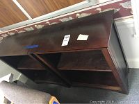 Two matching dark wood bookshelves side by side, showing top and side surfaces with visible wear and scratches.