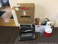 Lot overview showing Swingline CombBind C110E binding machine and box, toaster oven, cooler jug, glass vases, mugs, and glass bowl and dish
