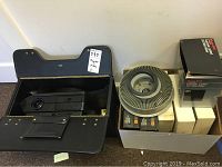 Kodak Ektagraphic III AMT projector inside Stebco case with projector lens visible and carousel tray on top.