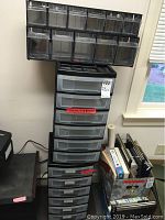 Two black plastic storage units each with six drawers stacked vertically. Drawers are semi-transparent. Units measure approximately 12x14x24 inches each.