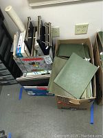 Green 11x14 post binders stacked and hanging file folders in a container.