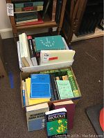 Overview of two boxes of various biology and ecology books stacked on the floor.