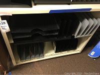 Overall view of shelf unit with black and gray desk trays and file racks inside various compartments.