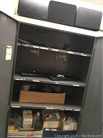 Wide shelving unit containing keyboards on middle shelves, box of staples and various small office supplies on bottom shelf