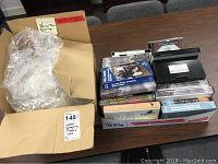 Box containing two bags of clear plastic water sample tubes and a box with multiple VHS tapes on environmental topics.