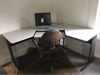 Corner computer desk with Dell monitor and office chair in room corner.