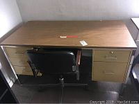 Wood grain metal desk with drawers and office chair in front