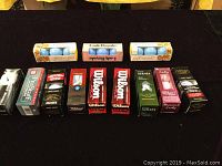 Photo of 12 boxes of golf balls arranged on table showing different brands and packaging including Golden Girl, Lady Royale, Wilson, Titleist, Nike, Pinnacle, and Strata.